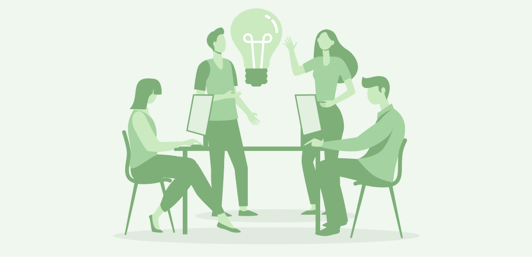 Cztery osoby pracują przy komputerach i omawiają pomysł